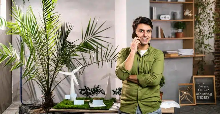 A sustainability consultant on the phone in an office with plants and renewable-energy models